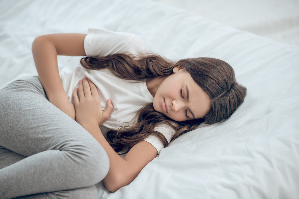 Girl with Upset Stomach Lying in Bed