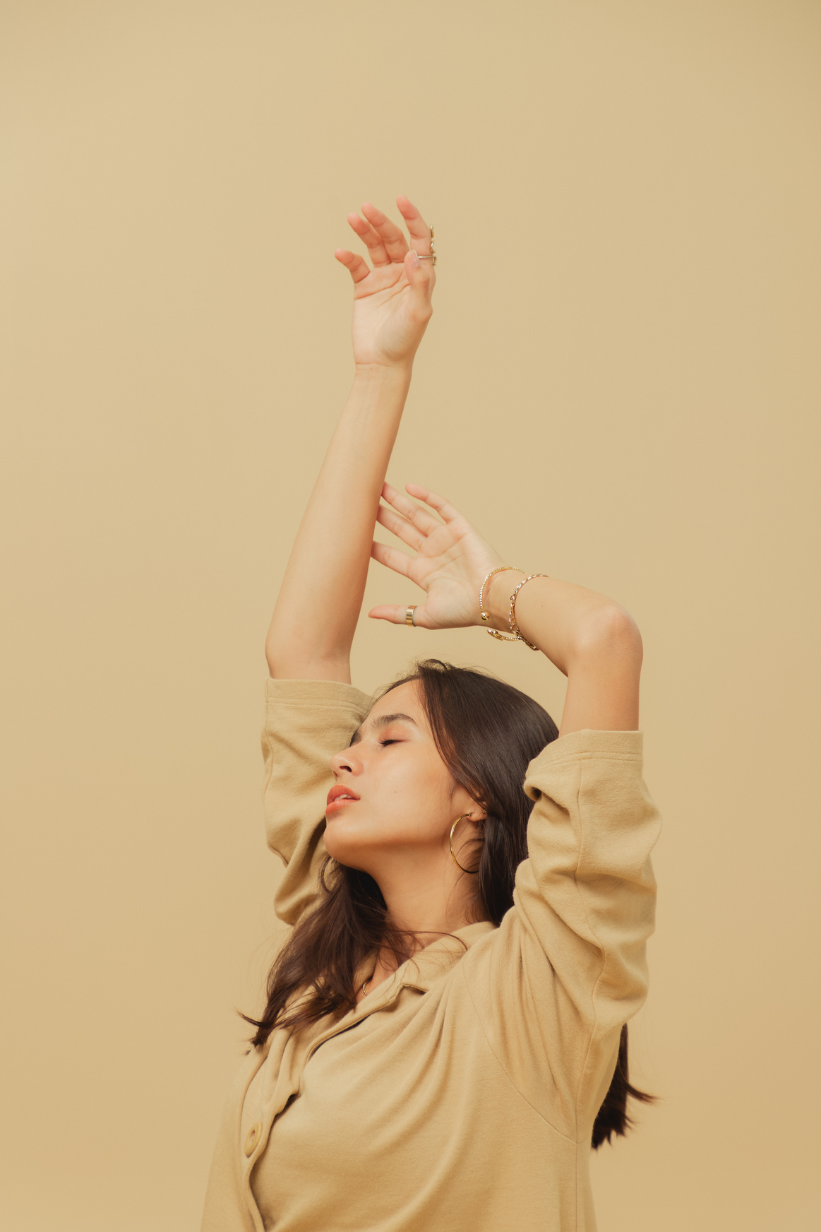 Woman in Beige Dress Shirt with Jewelry on Beige Background