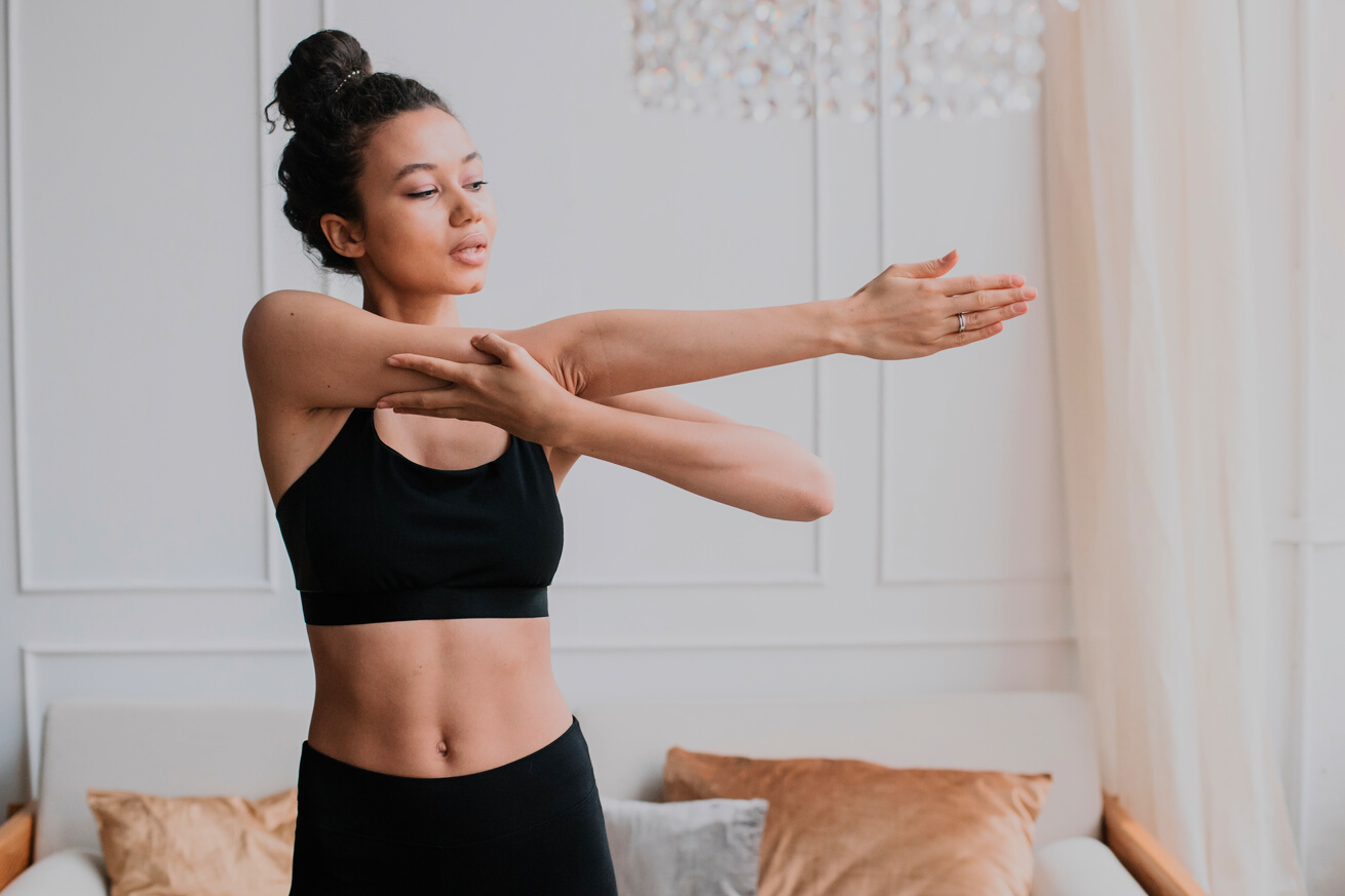 Woman in a Black Sports Bra Stretching Her Arm