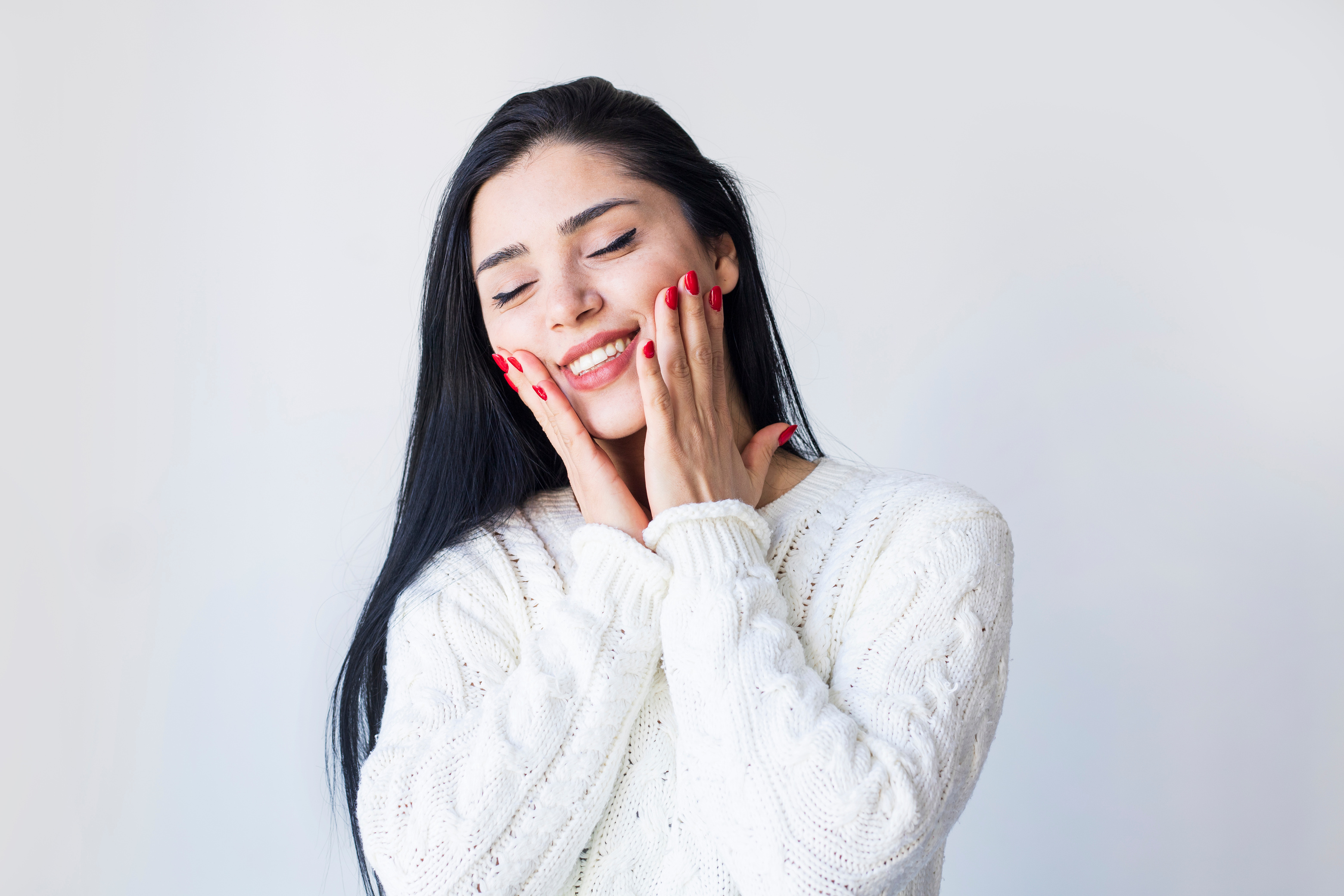 Young woman giving herself face massage on light background. Self love and self care